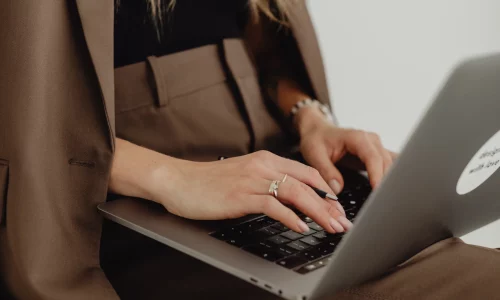 ujecie-z-gory-kobiece-dlonie-piszace-na-laptopie-na-kolanach-siedzac-na-krzesle-biurowym